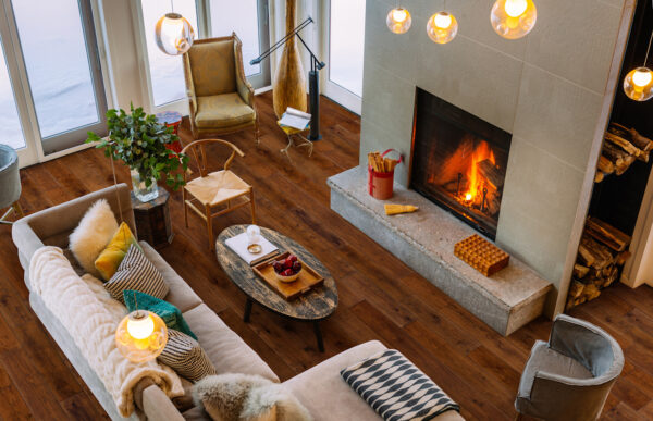 North American Cottage interior. Main floor open area of winter home North of Toronto, Canada. Featuring large windows with view of surrounding area, grand fireplace, modern mix of furniture and fabrics from around the world.